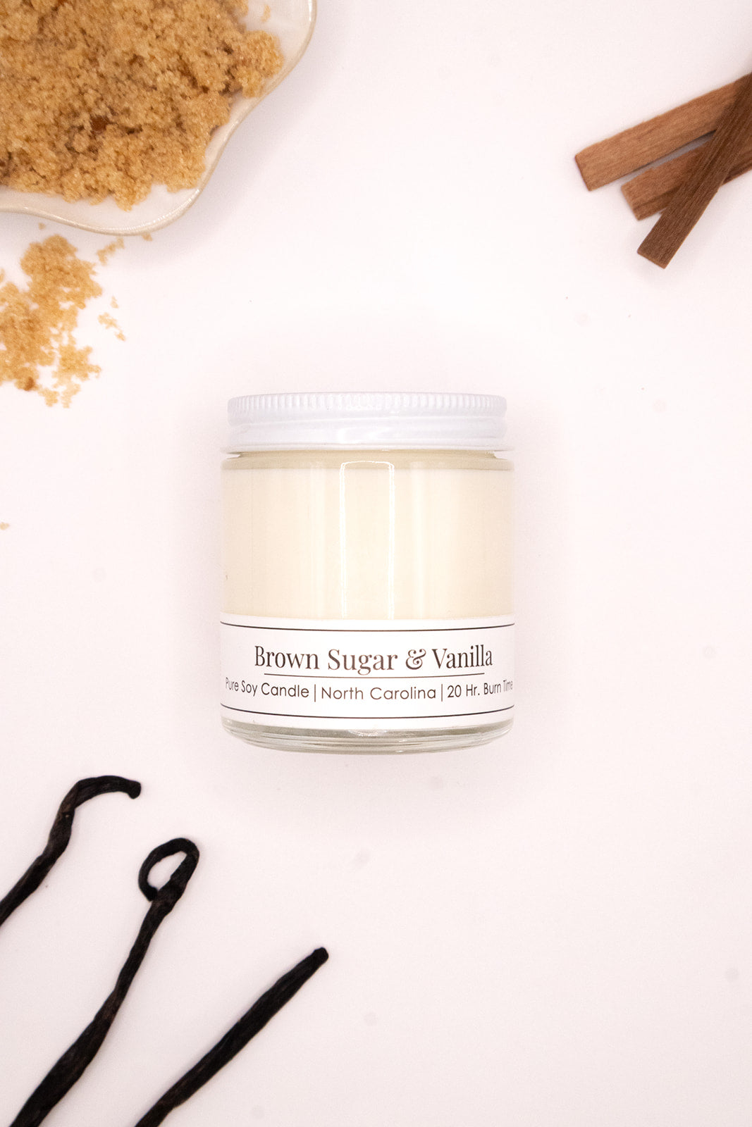 candle jar labeled 'Brown Sugar & Vanilla' with brown sugar and vanilla beans on a white background